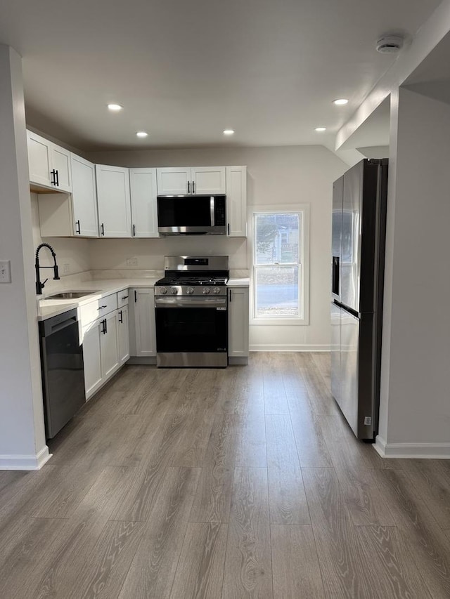 kitchen featuring sink, white cabinets, light hardwood / wood-style flooring, and appliances with stainless steel finishes