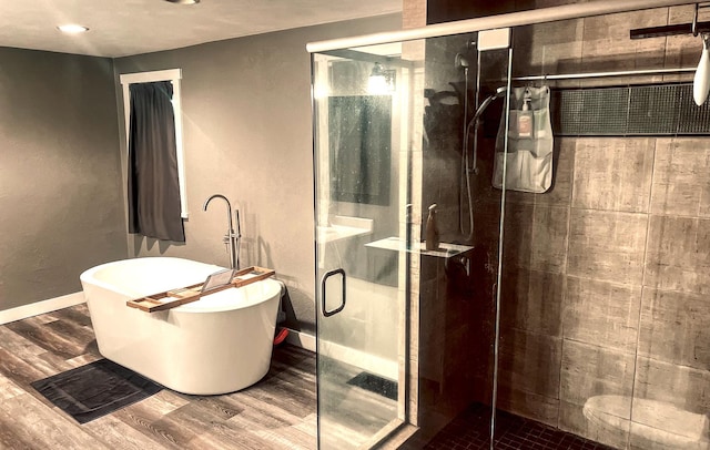 bathroom featuring plus walk in shower and hardwood / wood-style floors