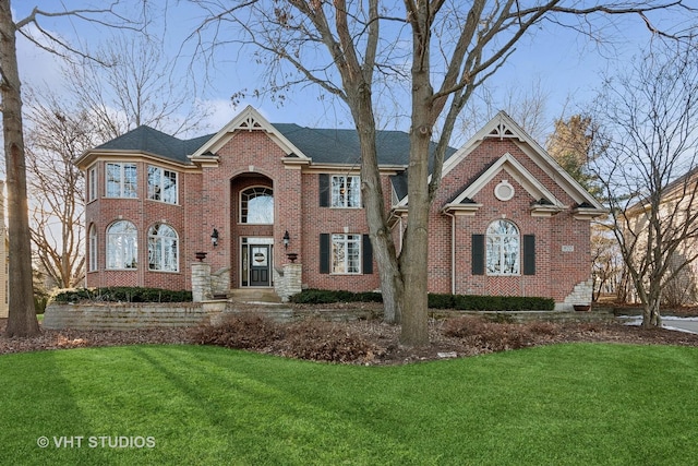 view of front of house with brick siding, a chimney, and a front yard