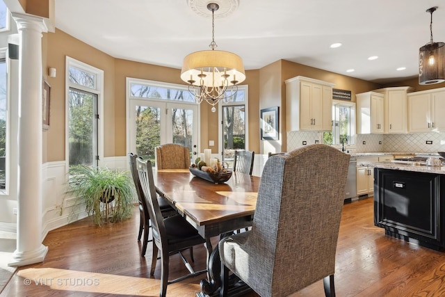 dining area featuring recessed lighting, wainscoting, ornate columns, and wood finished floors