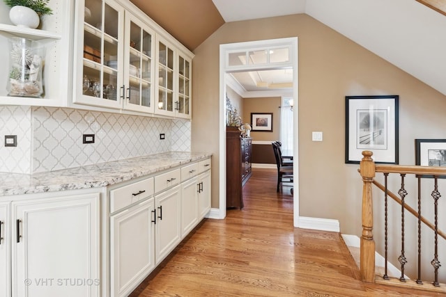 bar with vaulted ceiling, tasteful backsplash, light wood-style flooring, and baseboards