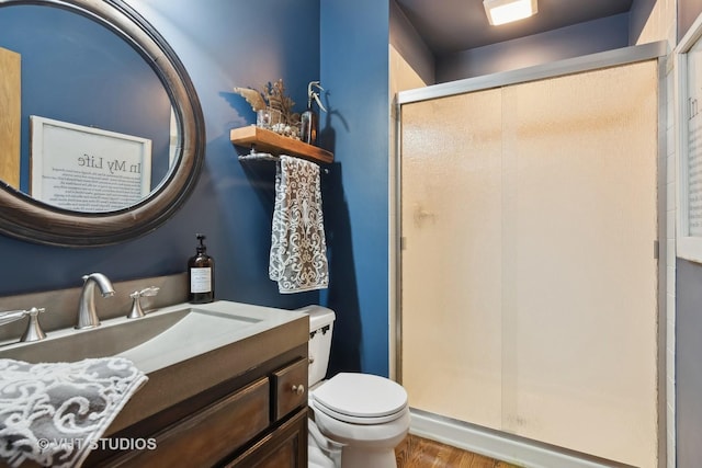 bathroom with toilet, a stall shower, and vanity