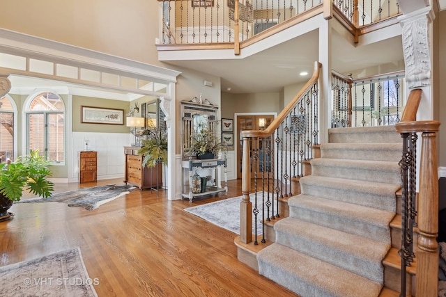 entryway featuring stairs, a towering ceiling, and wood finished floors