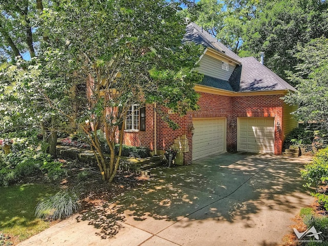 view of side of home with a garage, brick siding, driveway, and roof with shingles