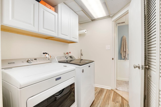 washroom with independent washer and dryer, cabinets, and light wood-type flooring