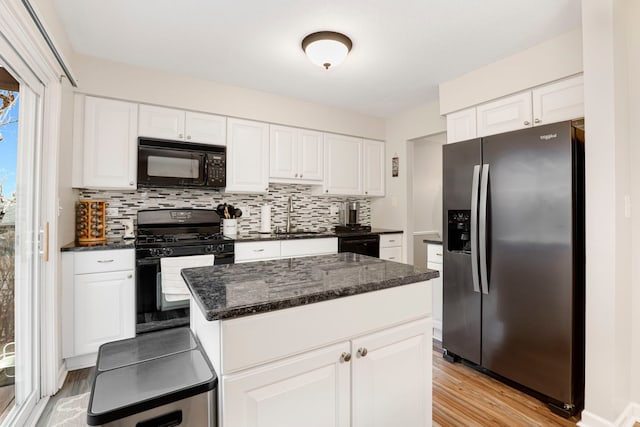 kitchen featuring a kitchen island, white cabinetry, sink, backsplash, and black appliances