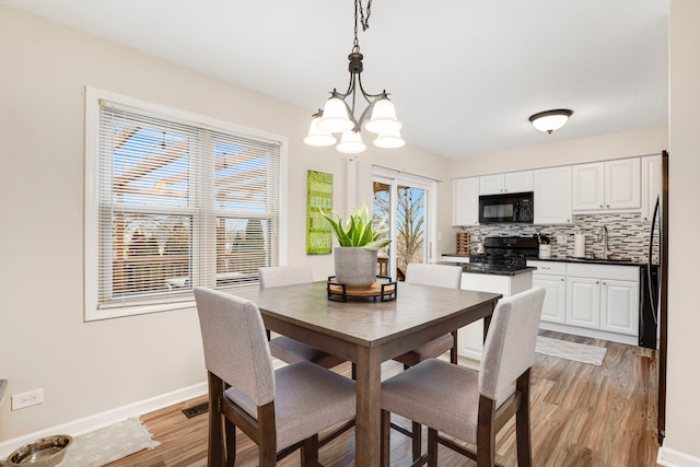 dining area featuring sink, light hardwood / wood-style floors, and a chandelier