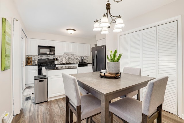 dining space featuring sink, light hardwood / wood-style flooring, and a chandelier