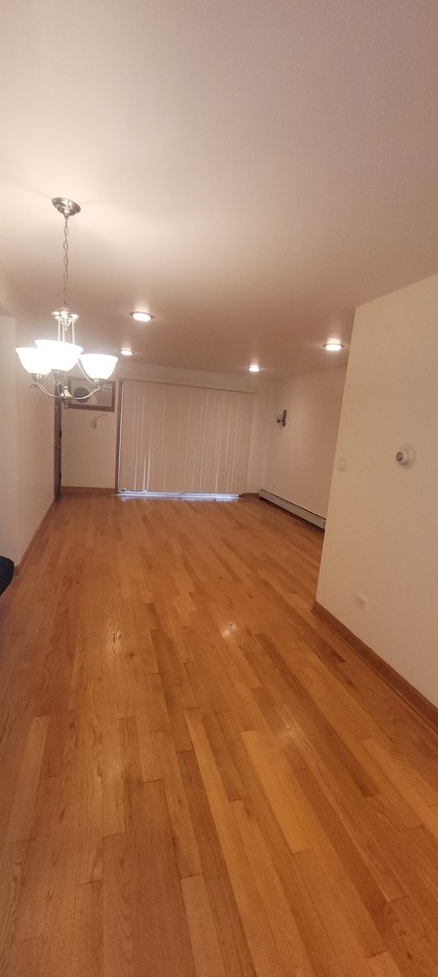 unfurnished room featuring an inviting chandelier and light wood-type flooring