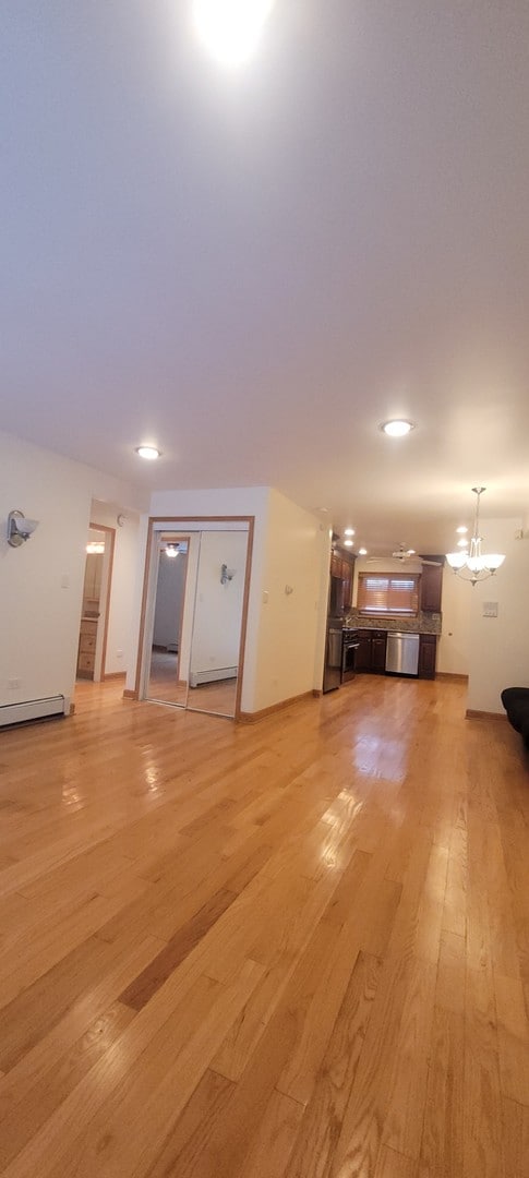 unfurnished living room with light wood-type flooring and a baseboard heating unit