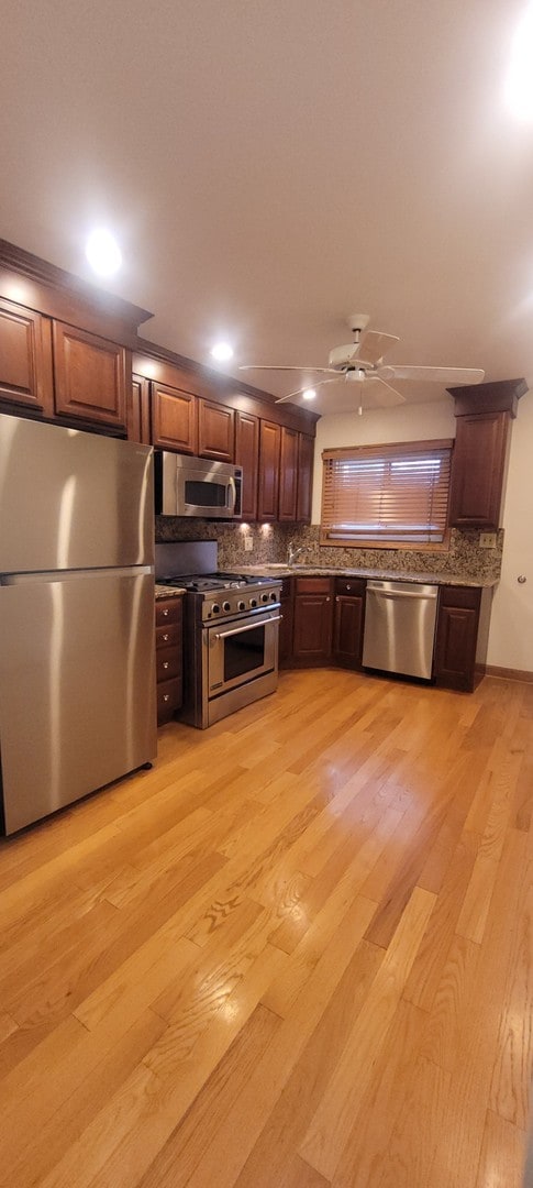 kitchen with decorative backsplash, light hardwood / wood-style flooring, and stainless steel appliances