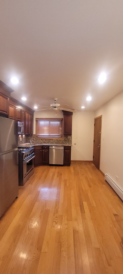 kitchen with backsplash, ceiling fan, stainless steel appliances, and light wood-type flooring