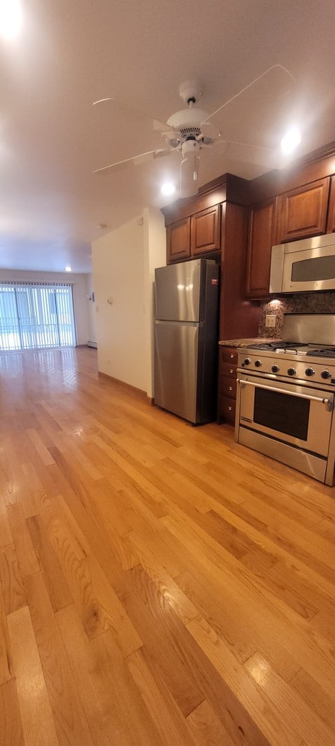 kitchen with tasteful backsplash, ceiling fan, light wood-type flooring, and appliances with stainless steel finishes