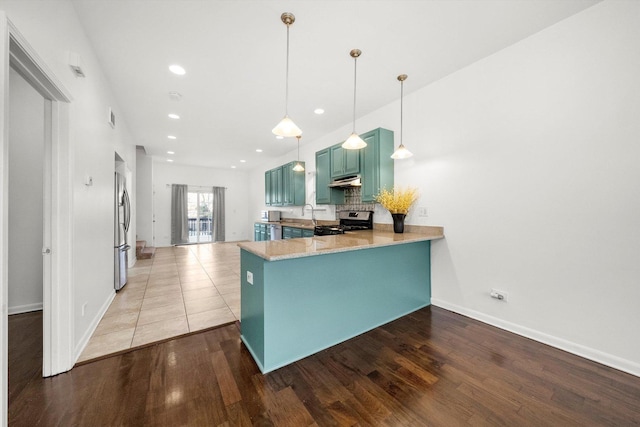 kitchen with kitchen peninsula, appliances with stainless steel finishes, decorative backsplash, pendant lighting, and hardwood / wood-style floors