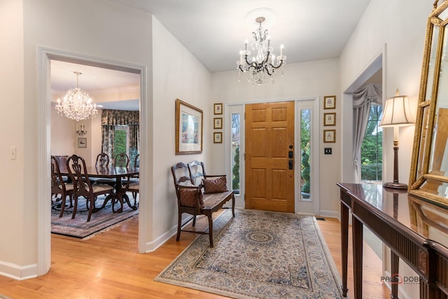 foyer entrance featuring light hardwood / wood-style flooring, a healthy amount of sunlight, and a notable chandelier