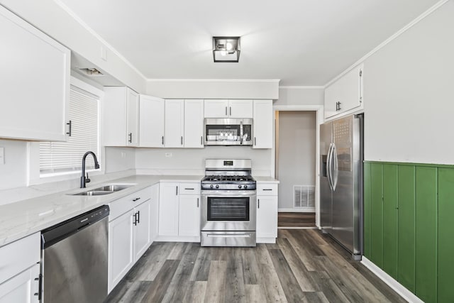 kitchen featuring light stone countertops, ornamental molding, stainless steel appliances, sink, and white cabinetry