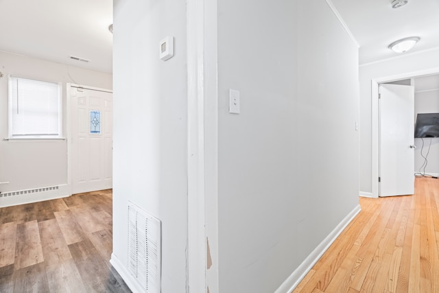 corridor featuring baseboard heating and hardwood / wood-style flooring