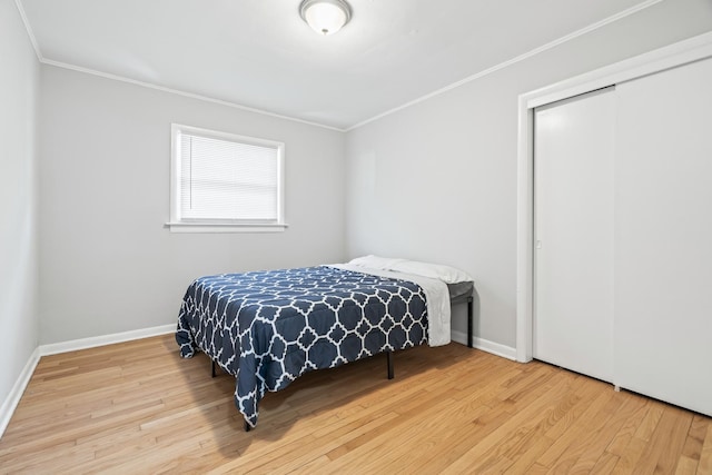 bedroom featuring hardwood / wood-style floors, crown molding, and a closet