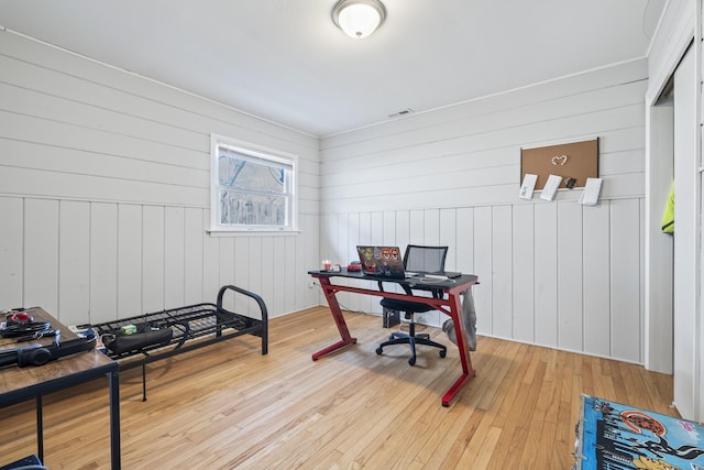 office space with light wood-type flooring and wooden walls