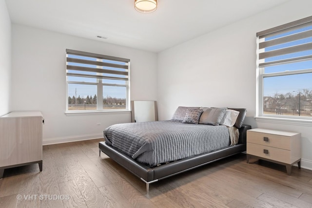 bedroom with multiple windows and hardwood / wood-style flooring