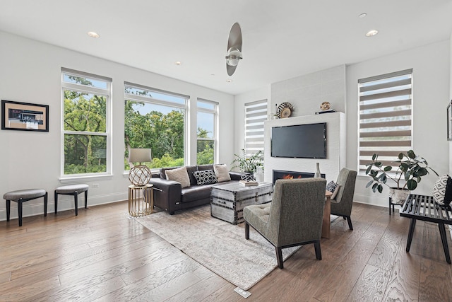 living room featuring a tile fireplace, hardwood / wood-style flooring, and ceiling fan