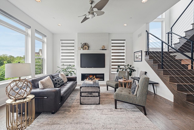 living room featuring a large fireplace, ceiling fan, and dark hardwood / wood-style flooring