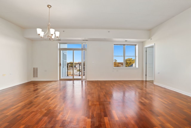 unfurnished room featuring a healthy amount of sunlight, dark wood-type flooring, and a chandelier