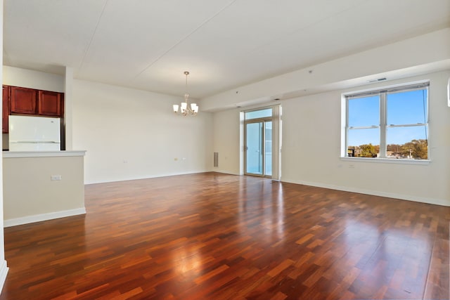 empty room featuring dark hardwood / wood-style flooring and a notable chandelier