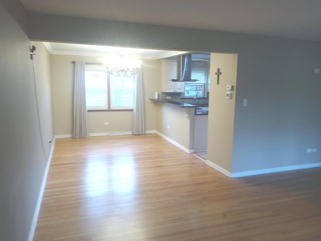 unfurnished living room featuring sink, ornamental molding, light hardwood / wood-style floors, and a notable chandelier