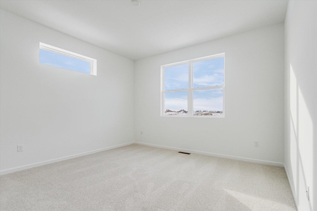 empty room featuring carpet floors, visible vents, and baseboards