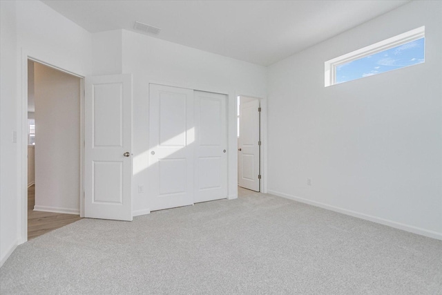 unfurnished bedroom with baseboards, visible vents, and light colored carpet