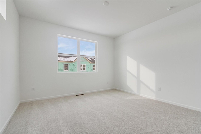 spare room with carpet floors, visible vents, and baseboards