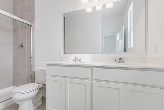 full bath featuring double vanity, a sink, toilet, and a shower stall