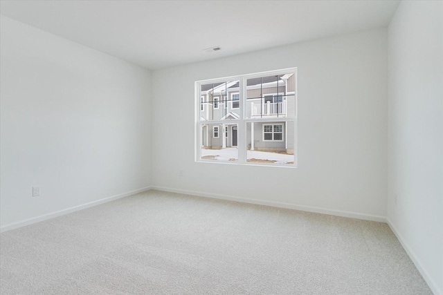 unfurnished room featuring carpet floors, visible vents, and baseboards