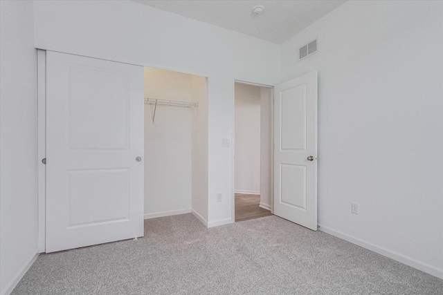 unfurnished bedroom featuring light carpet, a closet, visible vents, and baseboards