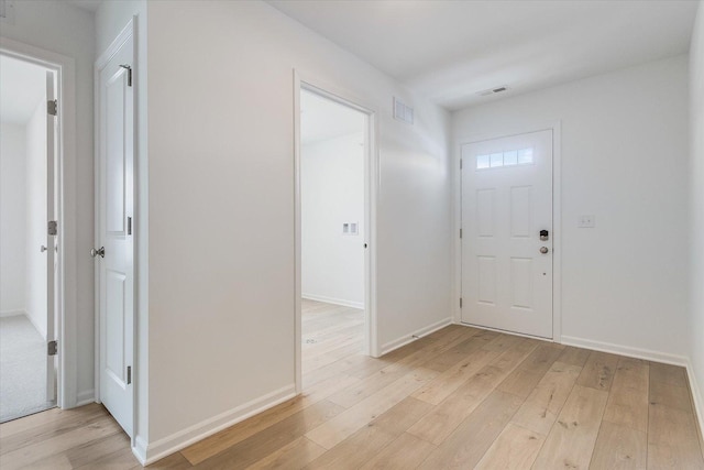 foyer entrance featuring baseboards, visible vents, and light wood-style floors