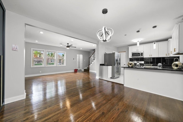 kitchen with white cabinetry, stainless steel appliances, hanging light fixtures, and tasteful backsplash