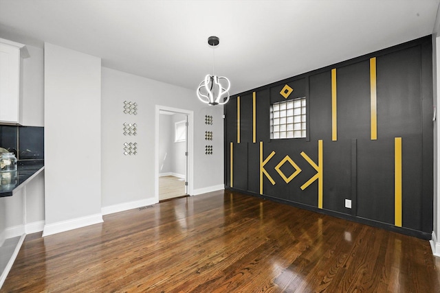 spare room with dark hardwood / wood-style flooring and a chandelier