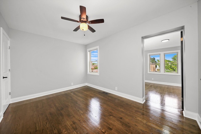 empty room with ceiling fan, dark hardwood / wood-style flooring, and a healthy amount of sunlight