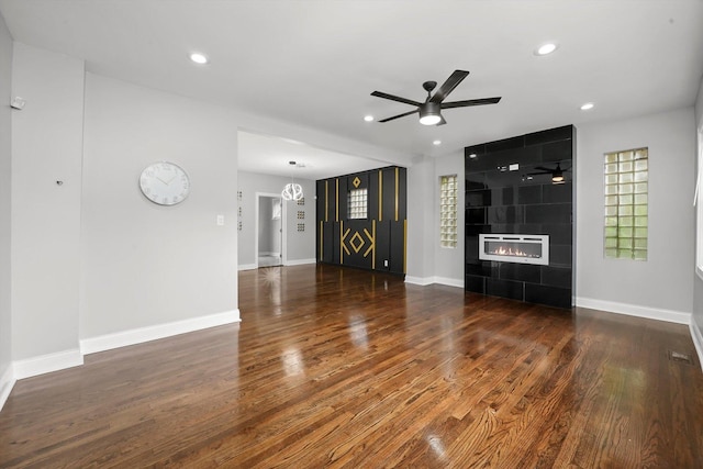 unfurnished living room featuring dark hardwood / wood-style floors, ceiling fan, and a tiled fireplace