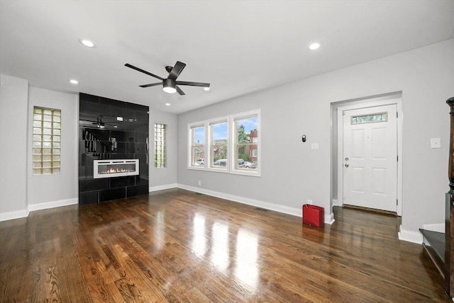 unfurnished living room with ceiling fan, dark hardwood / wood-style floors, and a tile fireplace