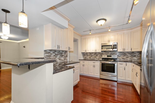 kitchen featuring decorative backsplash, a kitchen bar, track lighting, stainless steel appliances, and decorative light fixtures