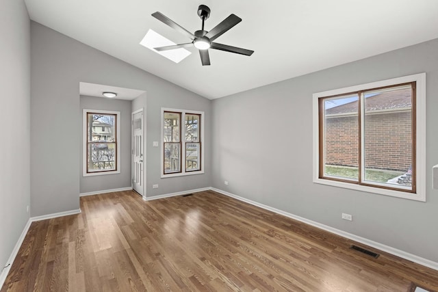 unfurnished room with hardwood / wood-style floors, ceiling fan, lofted ceiling with skylight, and a wealth of natural light