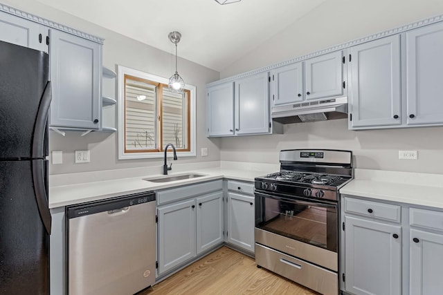 kitchen featuring stainless steel appliances, vaulted ceiling, sink, light hardwood / wood-style flooring, and hanging light fixtures