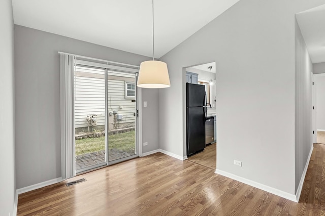 unfurnished dining area with plenty of natural light, light hardwood / wood-style floors, and lofted ceiling