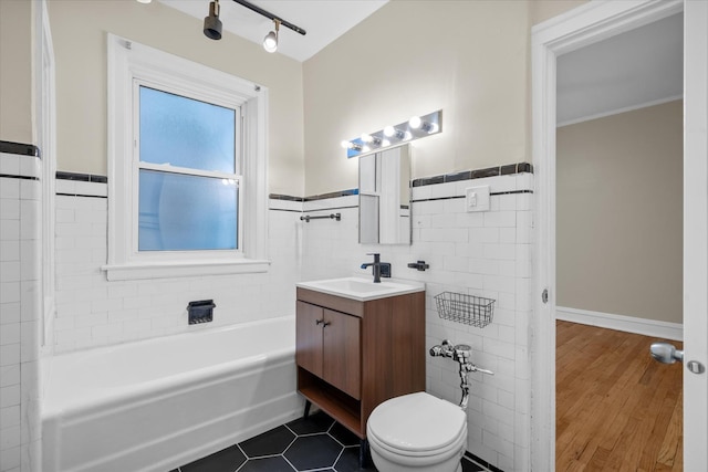 bathroom with vanity, a tub, tile walls, and toilet