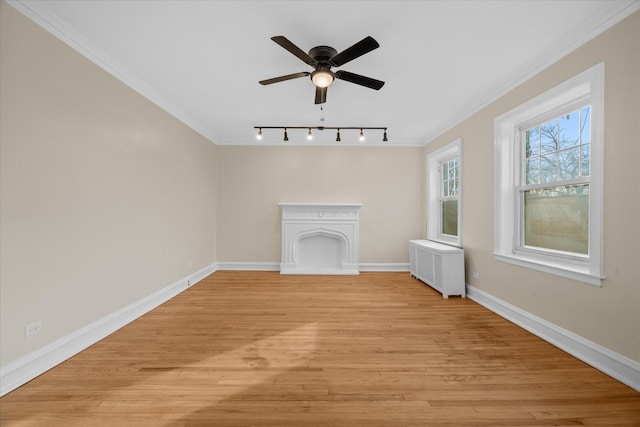 unfurnished living room with radiator, ceiling fan, crown molding, track lighting, and light hardwood / wood-style flooring