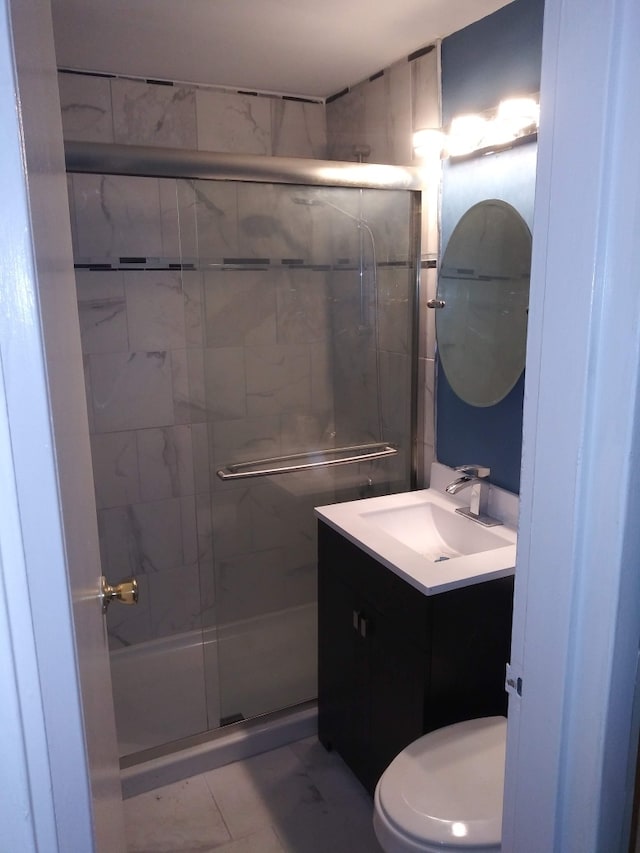 bathroom featuring vanity, toilet, and a shower with shower door