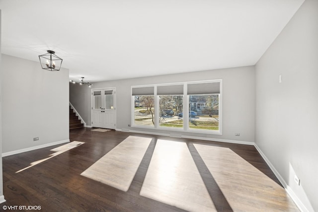 unfurnished living room with dark hardwood / wood-style floors and a notable chandelier