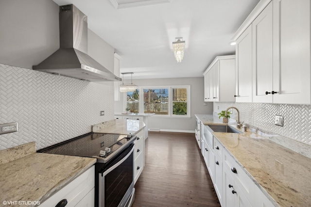 kitchen with stainless steel range with electric stovetop, pendant lighting, white cabinets, wall chimney range hood, and light stone countertops